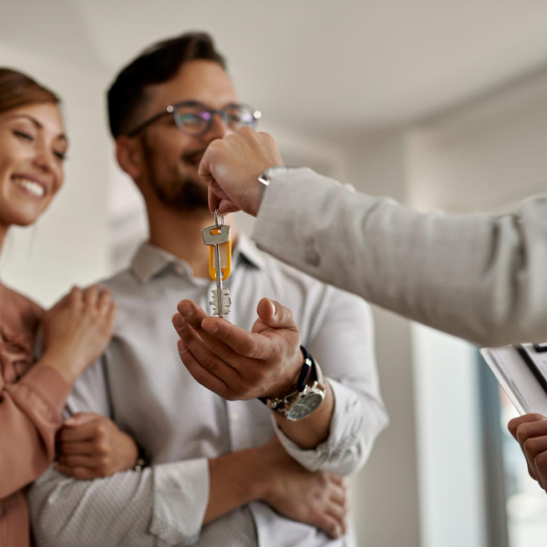 Courtier immobilier remettant les clés d’une maison à un couple lors d’un achat immobilier réussi